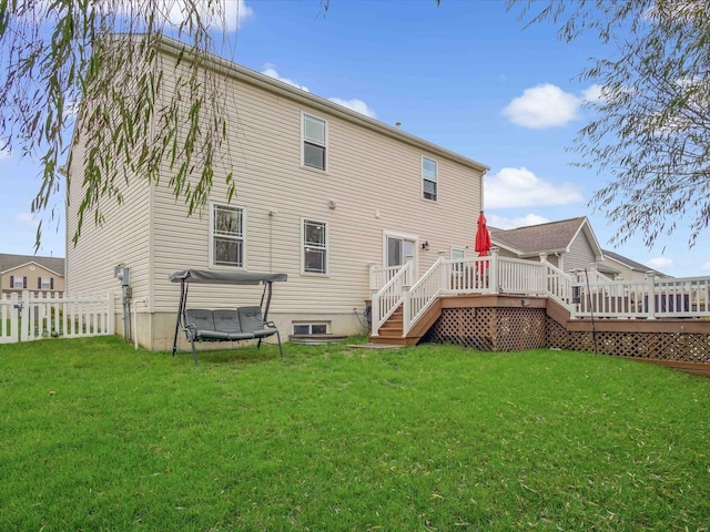 rear view of house with a wooden deck, a trampoline, and a lawn