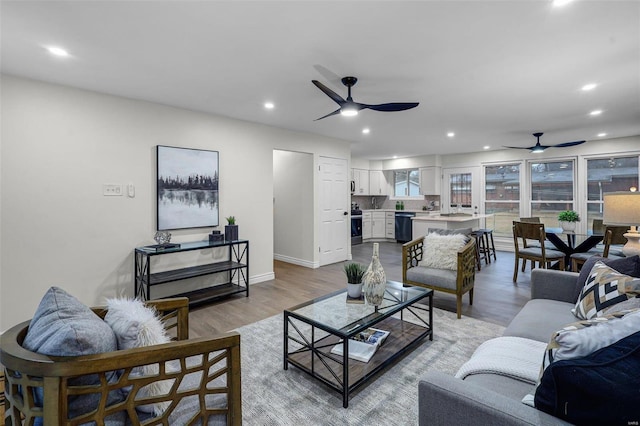 living room with ceiling fan and light hardwood / wood-style flooring