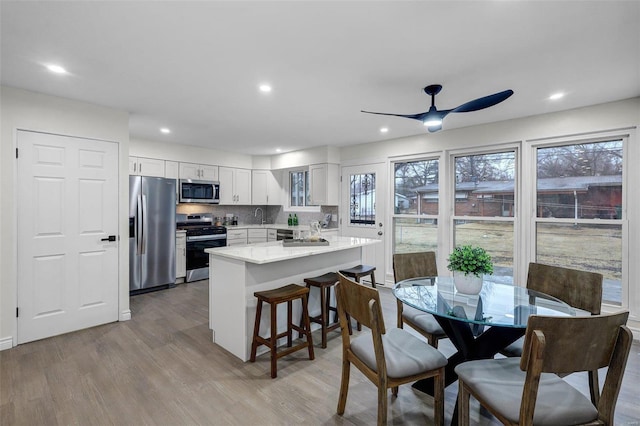 dining area featuring ceiling fan, sink, and light hardwood / wood-style flooring