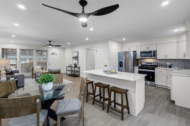 dining area with ceiling fan, sink, and light wood-type flooring