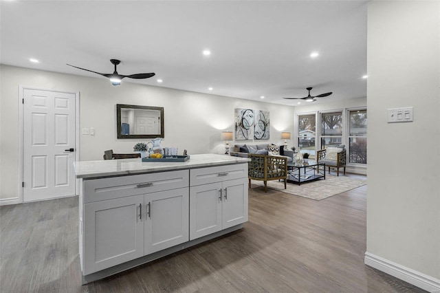 kitchen with white cabinets, a center island, ceiling fan, and light wood-type flooring