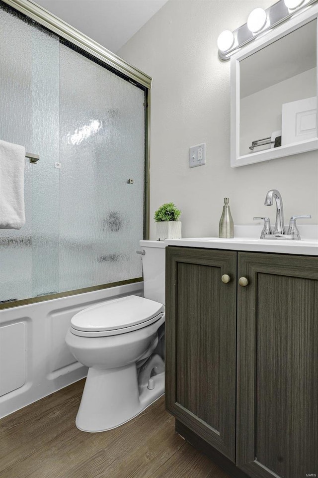 full bathroom featuring toilet, vanity, shower / bath combination with glass door, and hardwood / wood-style floors