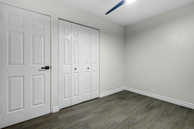 unfurnished bedroom with ceiling fan, dark hardwood / wood-style flooring, and a closet