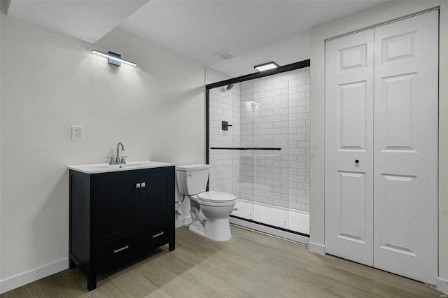 bathroom with hardwood / wood-style flooring, vanity, toilet, and a shower with door