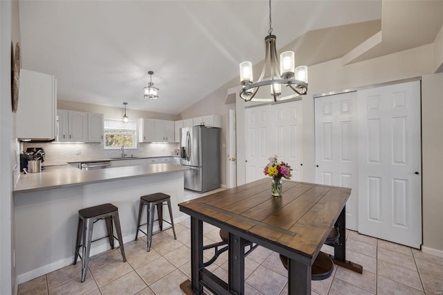 tiled dining area with an inviting chandelier, lofted ceiling, and sink