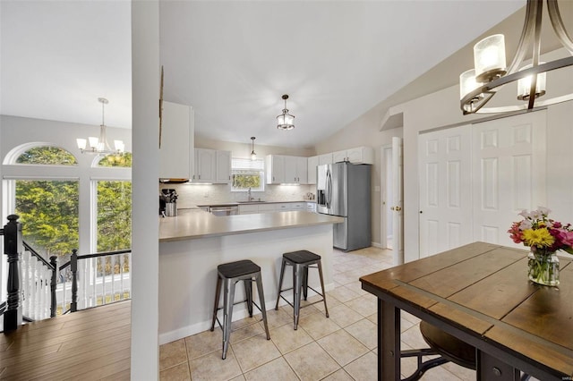 kitchen featuring sink, stainless steel fridge, tasteful backsplash, a notable chandelier, and white cabinets