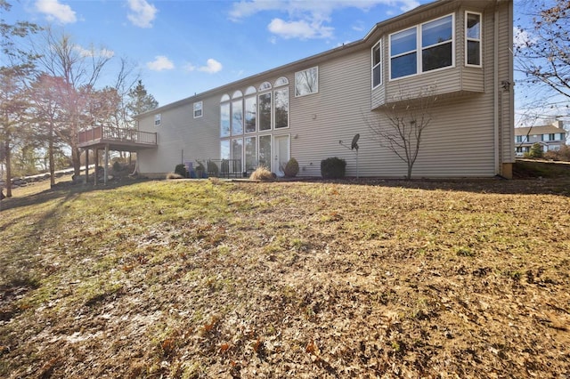 rear view of property with a wooden deck and a yard