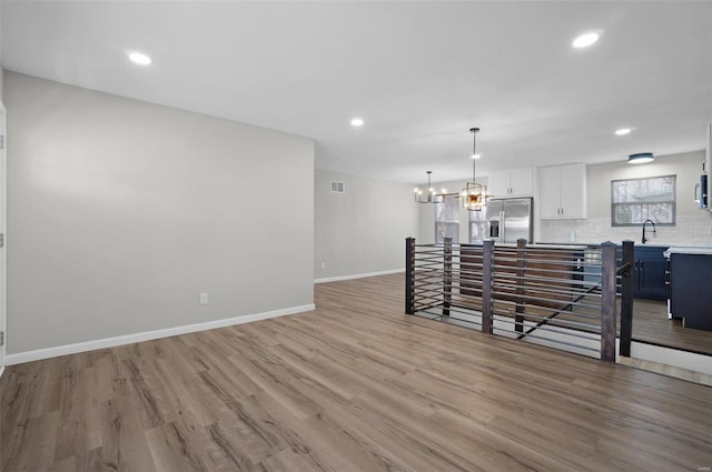 interior space with sink, a notable chandelier, and light wood-type flooring