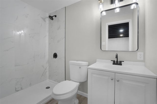 bathroom featuring vanity, hardwood / wood-style flooring, toilet, and a tile shower