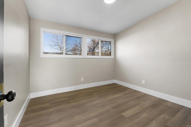 spare room featuring baseboards, a textured ceiling, and wood finished floors