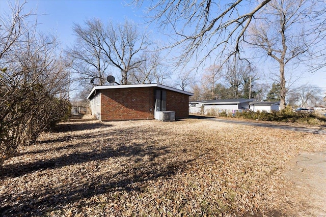 view of property exterior with cooling unit, an outbuilding, and brick siding