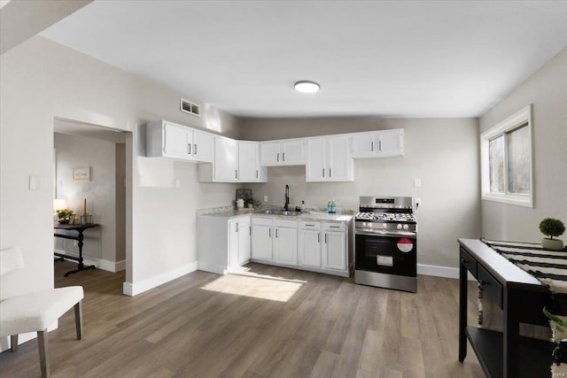 kitchen featuring wood finished floors, visible vents, a sink, white cabinetry, and stainless steel gas stove