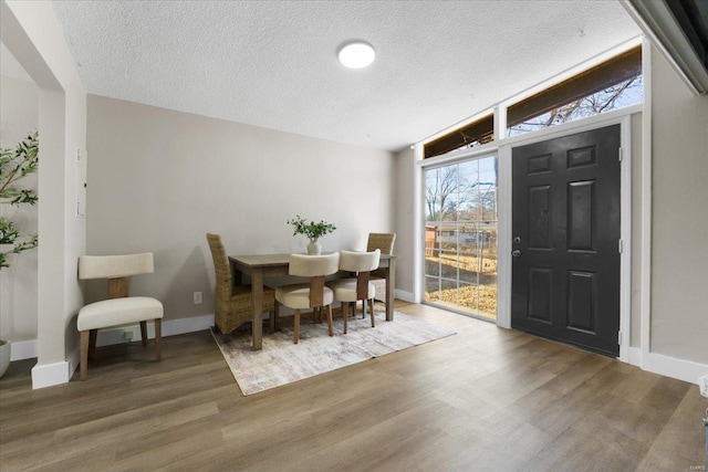 dining room with wood finished floors, baseboards, and a textured ceiling