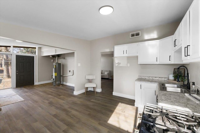 kitchen featuring visible vents, a sink, dark wood-style floors, water heater, and white cabinetry