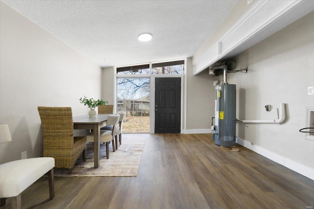 dining space featuring water heater, a textured ceiling, baseboards, and wood finished floors