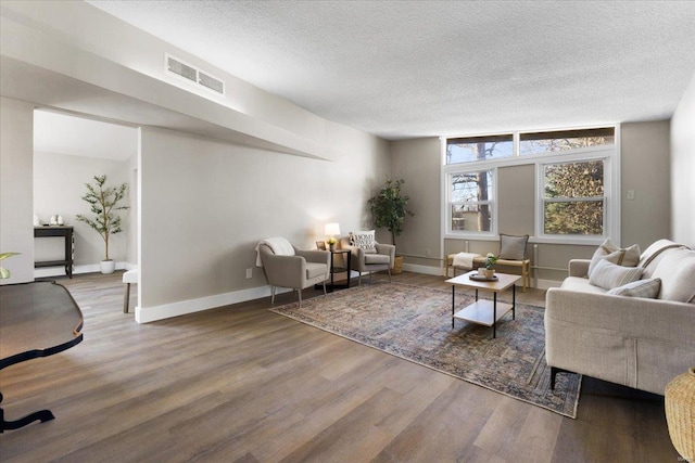 interior space featuring visible vents, a textured ceiling, baseboards, and wood finished floors