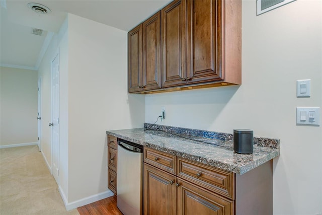 kitchen featuring dishwasher, light carpet, ornamental molding, and dark stone countertops