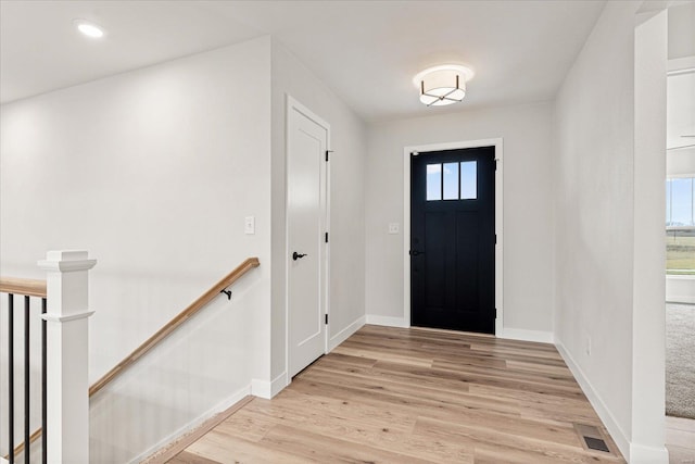 foyer with light wood finished floors, baseboards, and visible vents