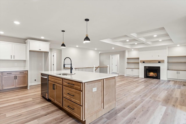 kitchen with an island with sink, brown cabinets, open floor plan, light countertops, and a sink