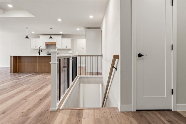 stairway featuring baseboards, wood finished floors, and recessed lighting