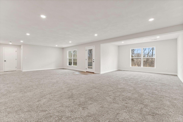 unfurnished living room with a healthy amount of sunlight, recessed lighting, and light colored carpet