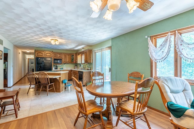 dining space featuring wine cooler, a textured ceiling, and light wood-type flooring