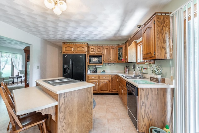 kitchen with sink, light tile patterned floors, a kitchen breakfast bar, and black appliances