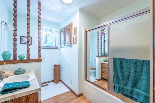 full bathroom with vanity, combined bath / shower with glass door, and toilet