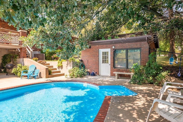 view of swimming pool with a grill, an outdoor structure, and a patio