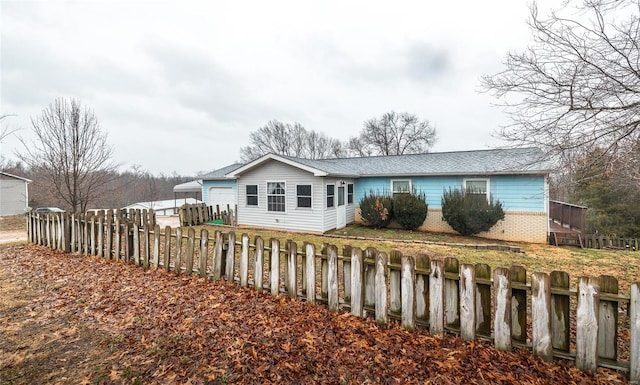 back of house featuring brick siding and a fenced front yard