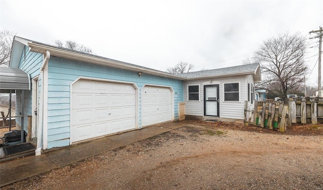 garage featuring fence and dirt driveway