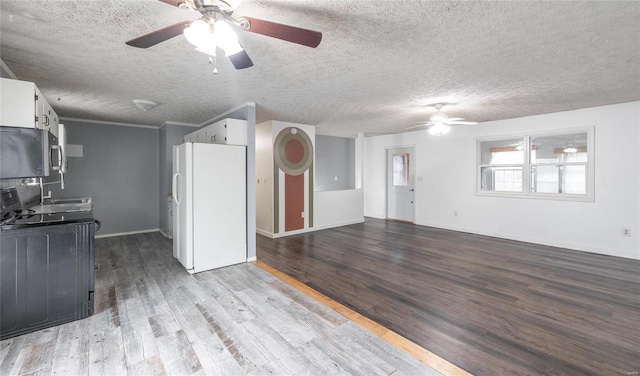 kitchen with white cabinets, wood finished floors, and freestanding refrigerator