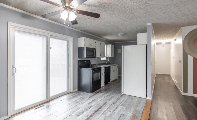 kitchen with light wood finished floors, visible vents, crown molding, a textured ceiling, and black appliances