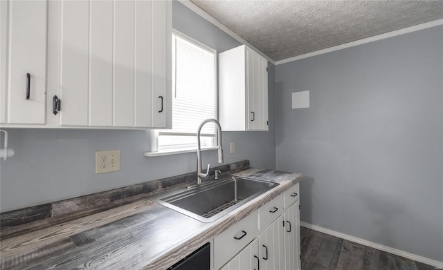 kitchen with dark wood finished floors, white cabinets, ornamental molding, a textured ceiling, and a sink