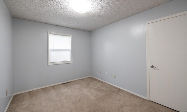 unfurnished room with carpet floors, baseboards, and a textured ceiling