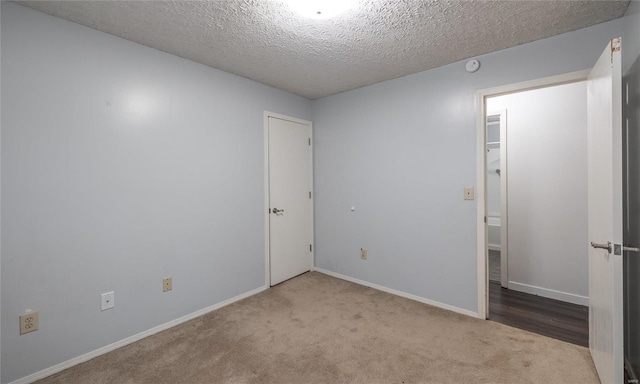 unfurnished bedroom featuring carpet, a closet, a textured ceiling, and baseboards