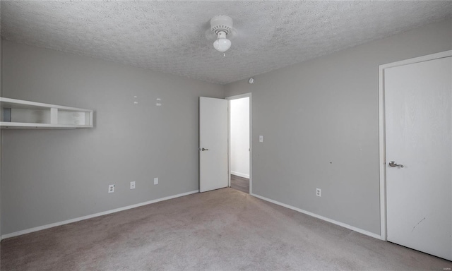 carpeted empty room with a textured ceiling and baseboards