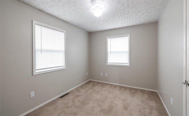 unfurnished room with carpet floors, visible vents, a textured ceiling, and baseboards