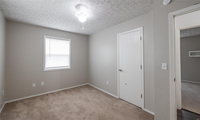 unfurnished bedroom featuring carpet floors, a textured ceiling, and baseboards