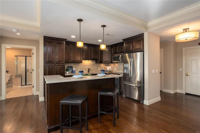 kitchen with a kitchen island, appliances with stainless steel finishes, a breakfast bar, decorative light fixtures, and dark brown cabinetry