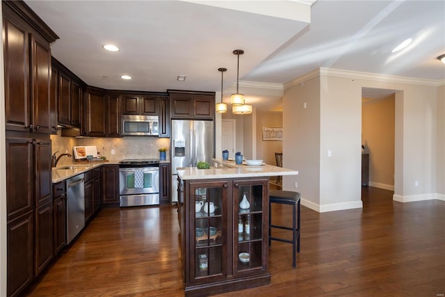 kitchen featuring dark wood-type flooring, stainless steel appliances, a kitchen breakfast bar, dark brown cabinetry, and decorative light fixtures