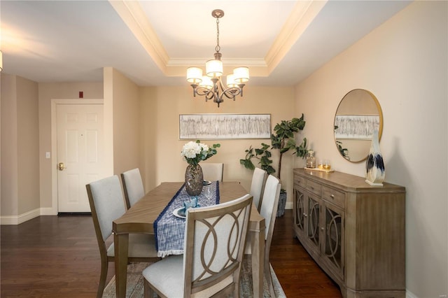 dining room with dark wood-type flooring, a raised ceiling, and a chandelier