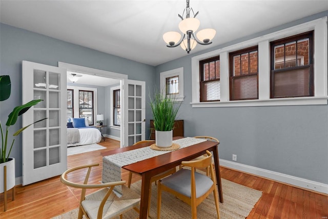 dining space with an inviting chandelier, hardwood / wood-style floors, and french doors