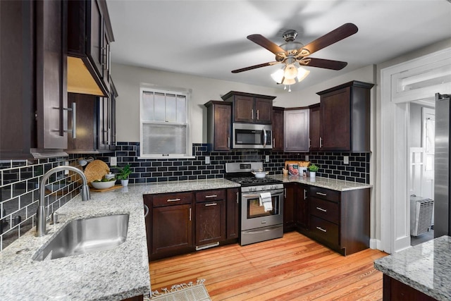 kitchen featuring light stone counters, appliances with stainless steel finishes, sink, and light hardwood / wood-style flooring