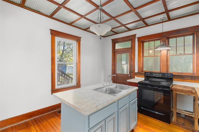 kitchen featuring light countertops, light wood-type flooring, a sink, and black range with electric cooktop
