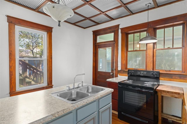 kitchen with a sink, black electric range oven, hanging light fixtures, and light countertops