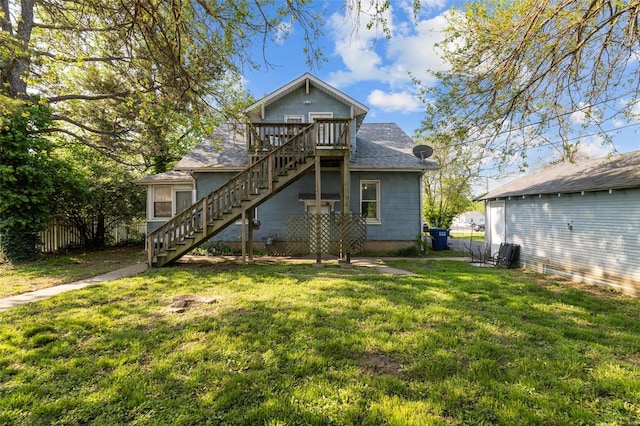rear view of house with roof with shingles, a deck, stairway, fence, and a yard