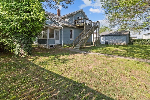 back of property with a chimney, a lawn, a wooden deck, a sunroom, and stairway