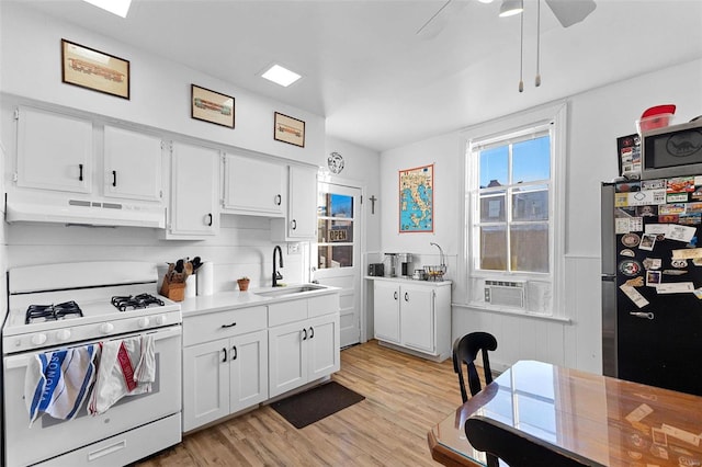 kitchen with stainless steel fridge, sink, white range with gas stovetop, and white cabinets