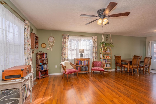 sitting room featuring hardwood / wood-style flooring, ceiling fan, and a textured ceiling